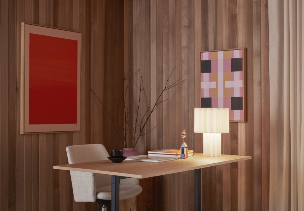 detail of framed sound-absorbing pink and red works of art on wood wall