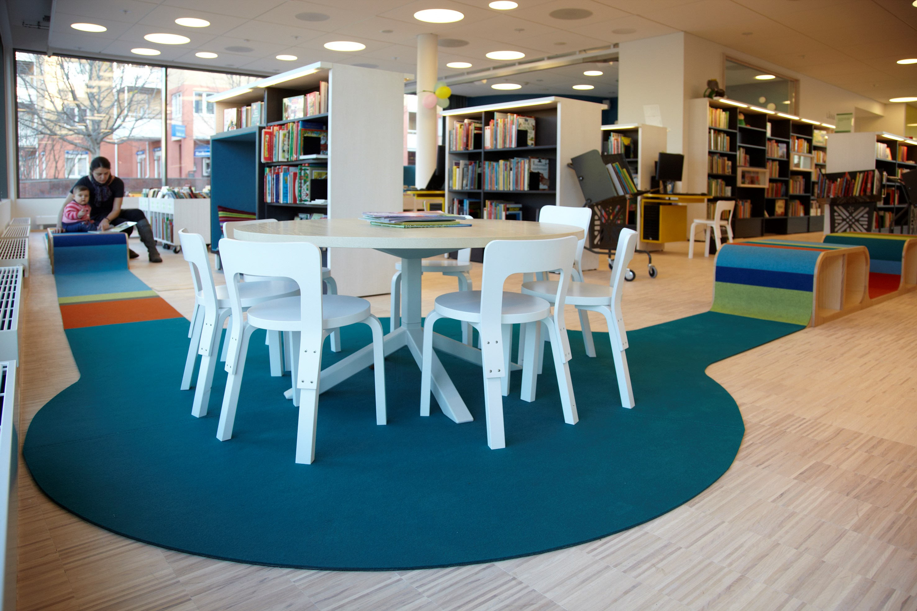 mother and child reading in library on colorful acoustic Fraster felt rug