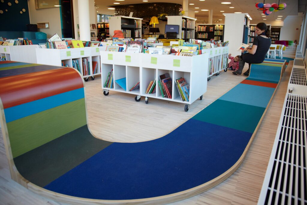 mother and child reading in library on colorful acoustic wool felt rug